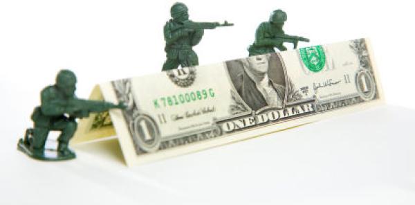 Toy soldiers hiding behind dollar bill