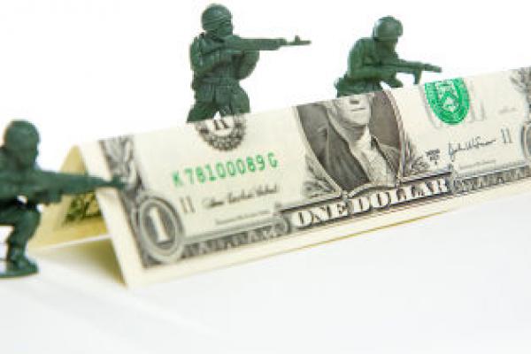 Toy soldiers hiding behind dollar bill
